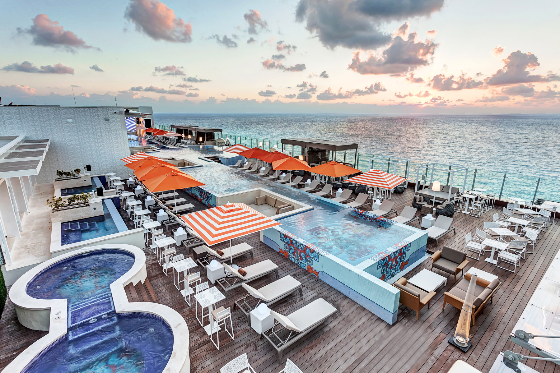 a pool and chairs on a deck overlooking the ocean
