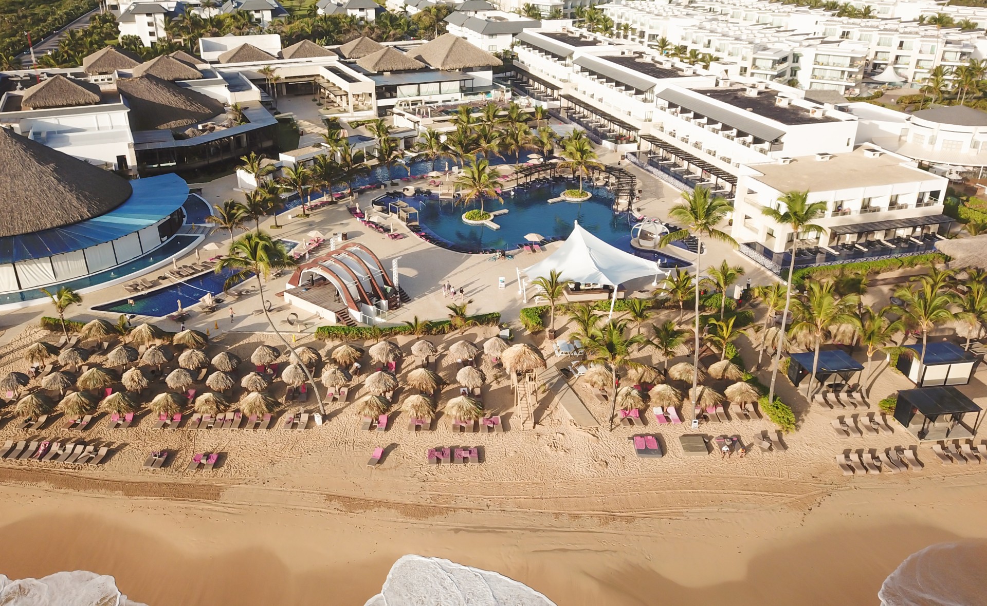 a swimming pool and a beach with buildings and a large pool