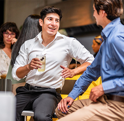 a man holding a drink and talking to another man