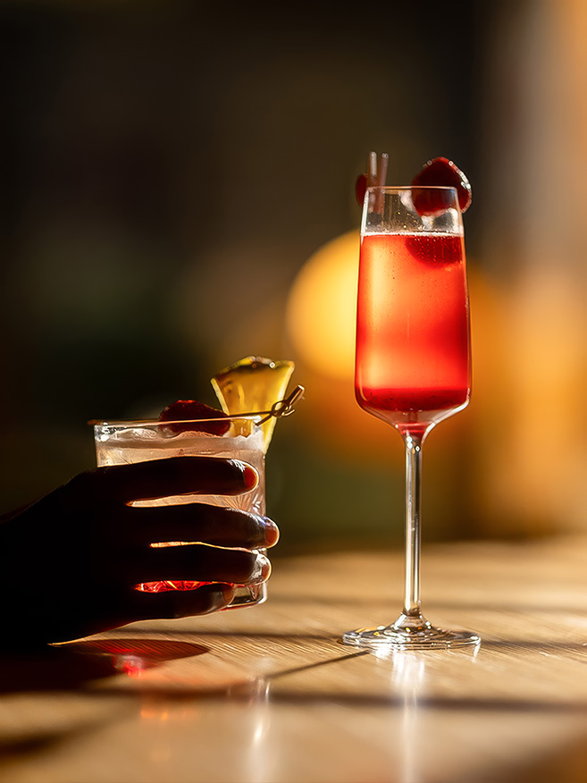 a hand holding a glass of liquid next to a glass of liquid
