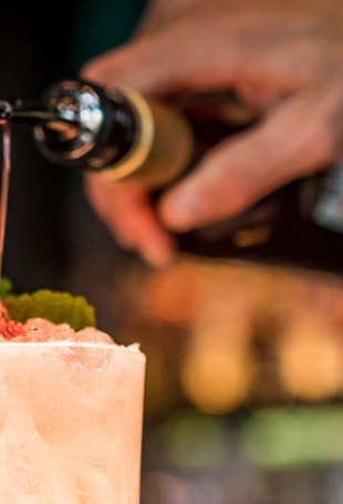 a person pouring liquid into a drink