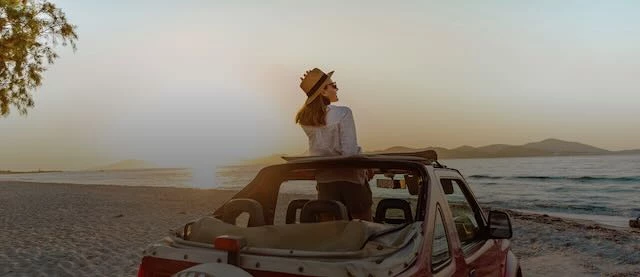 a woman standing in a car on a beach