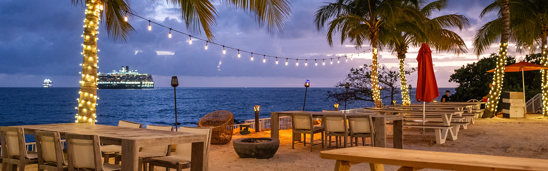 a beach with a fire pit and chairs