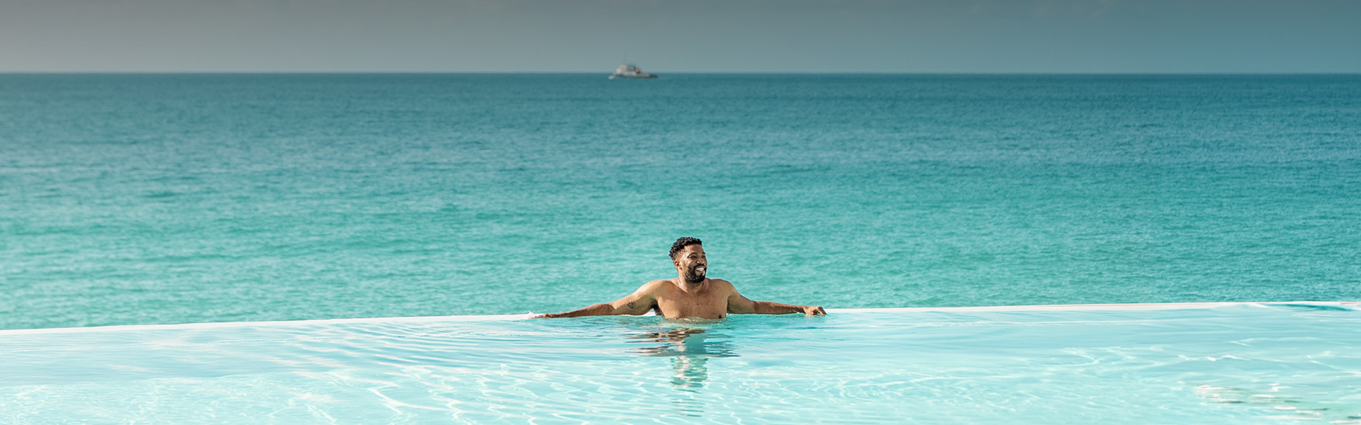 a man in a pool with a boat in the background