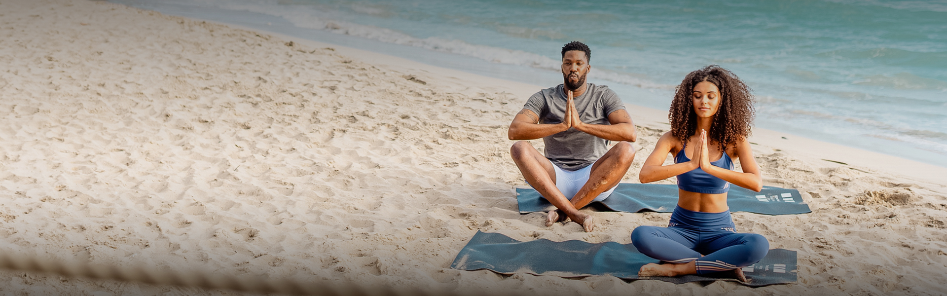 a man sitting on a beach with his hands together