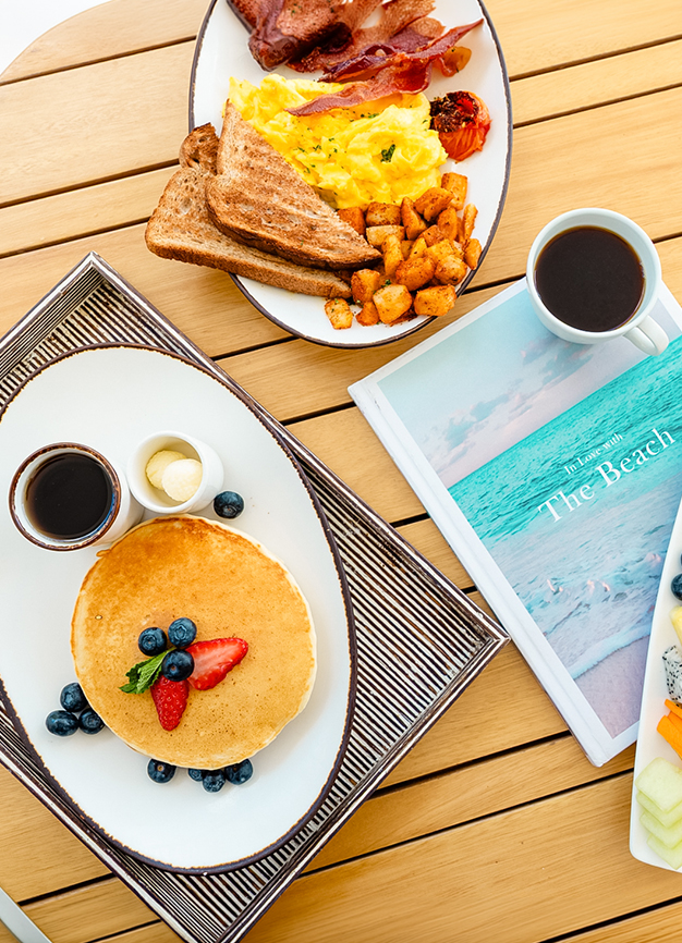 a plate of pancakes and a cup of coffee next to a magazine