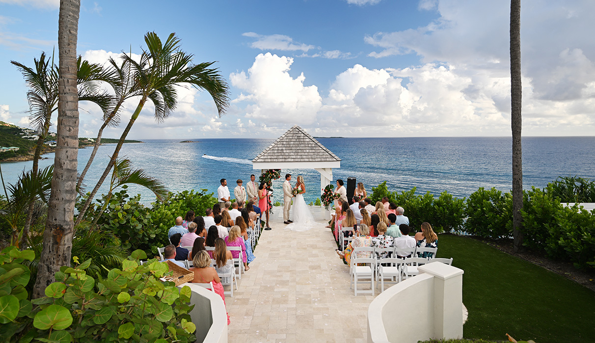 a wedding ceremony with a group of people and a gazebo