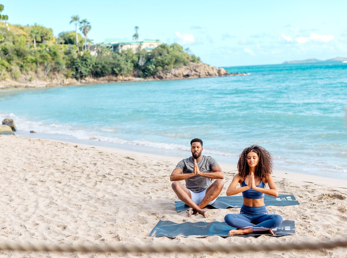 a man and woman sitting on the beach with their hands together