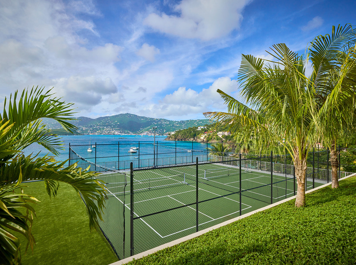 a tennis court with a body of water in the background