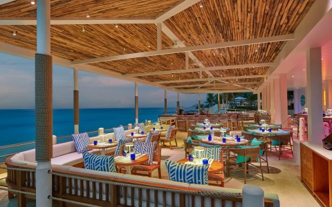 a restaurant with tables and chairs on a deck overlooking the ocean