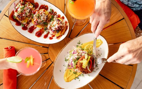 a person holding a fork and knife to a plate of food