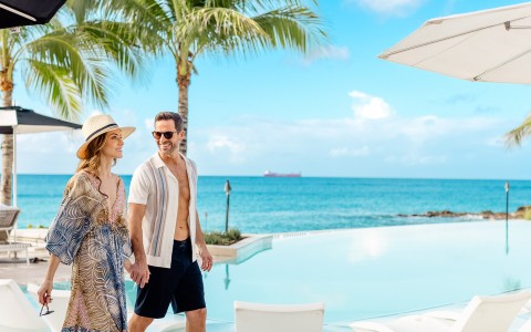 a man and woman holding hands by a pool