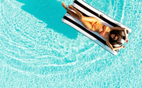 a woman in a garment lying on a raft in a pool