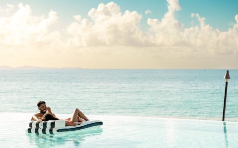 a couple lying on a floating raft in a pool