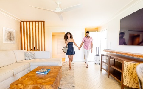 a man and woman holding hands and walking in a room