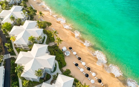 a beach with white buildings and umbrellas