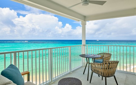 a deck with chairs and table overlooking the ocean