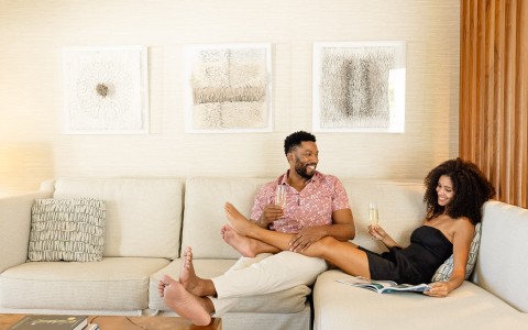 a man and woman sitting on a couch with champagne glasses