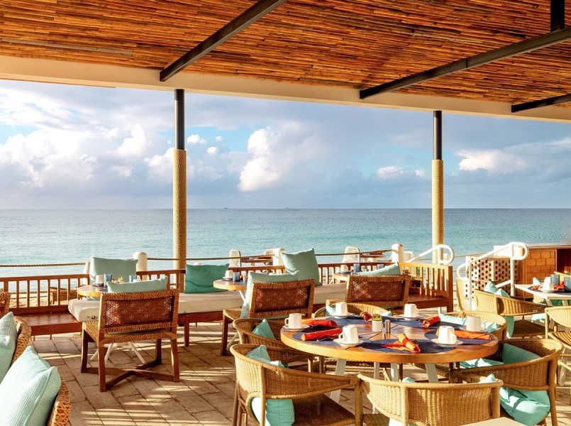a restaurant with tables and chairs on a patio overlooking the ocean