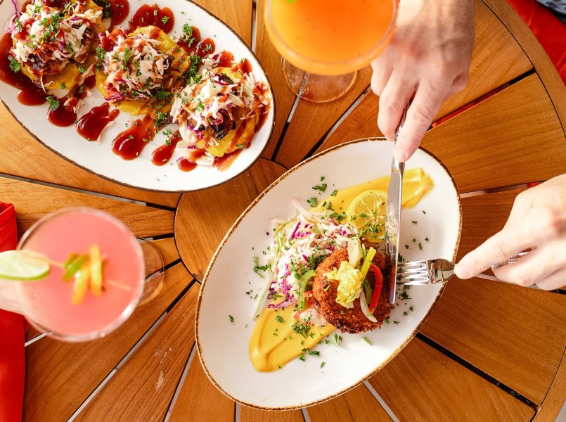 a person holding a fork and knife to a plate of food