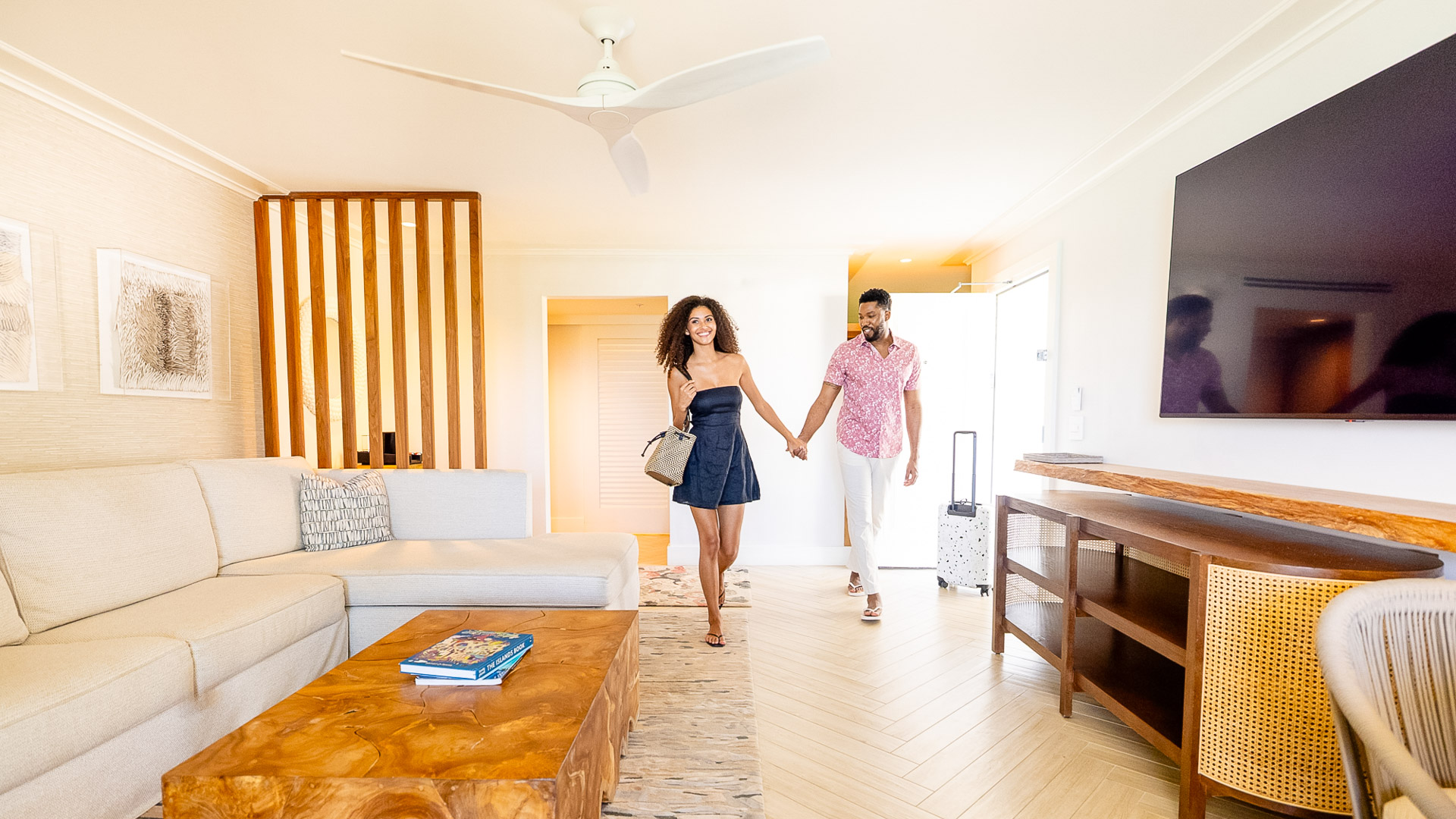 a man and woman holding hands and walking in a room