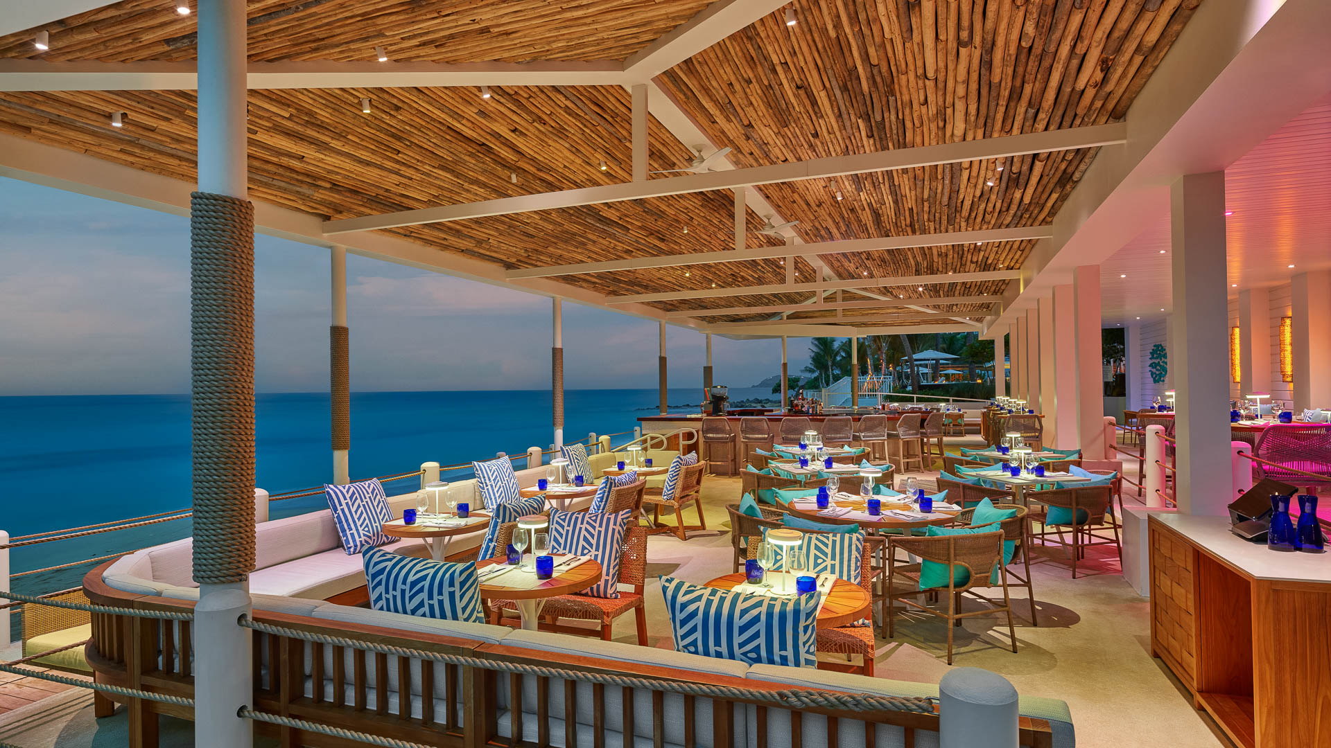 a restaurant with tables and chairs on a deck overlooking the ocean