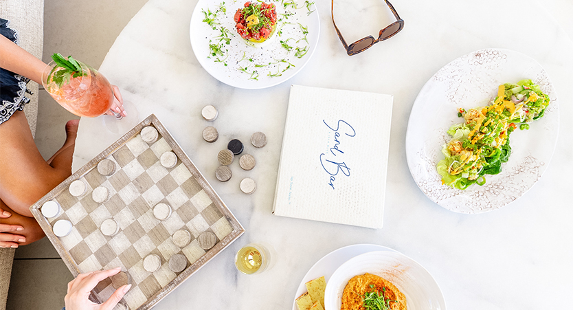 a table with plates of food and a checkerboard and glasses