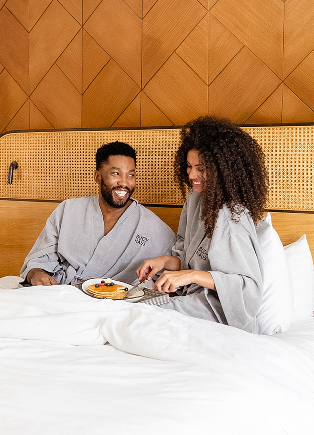 a man and woman in bathrobes sitting in bed