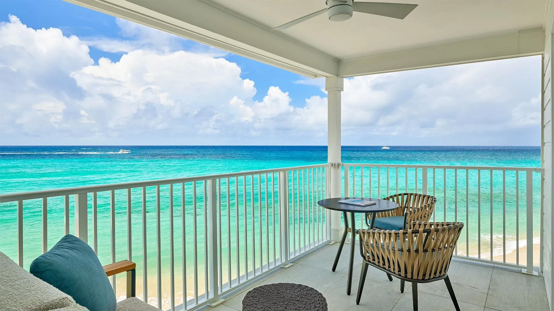 a deck with chairs and table overlooking the ocean