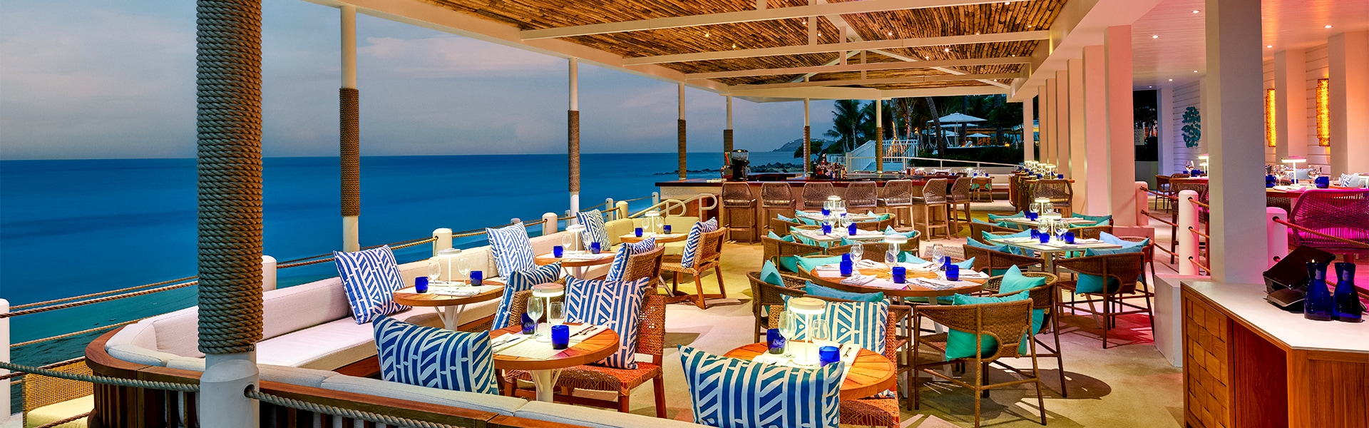 a restaurant with tables and chairs on a deck overlooking the ocean