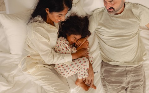 a man and woman lying on a bed with a baby