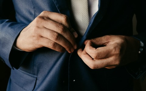 a close up of hands buttoning a suit