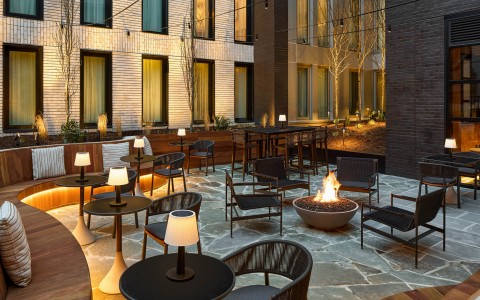 a patio with chairs and tables and a fire pit