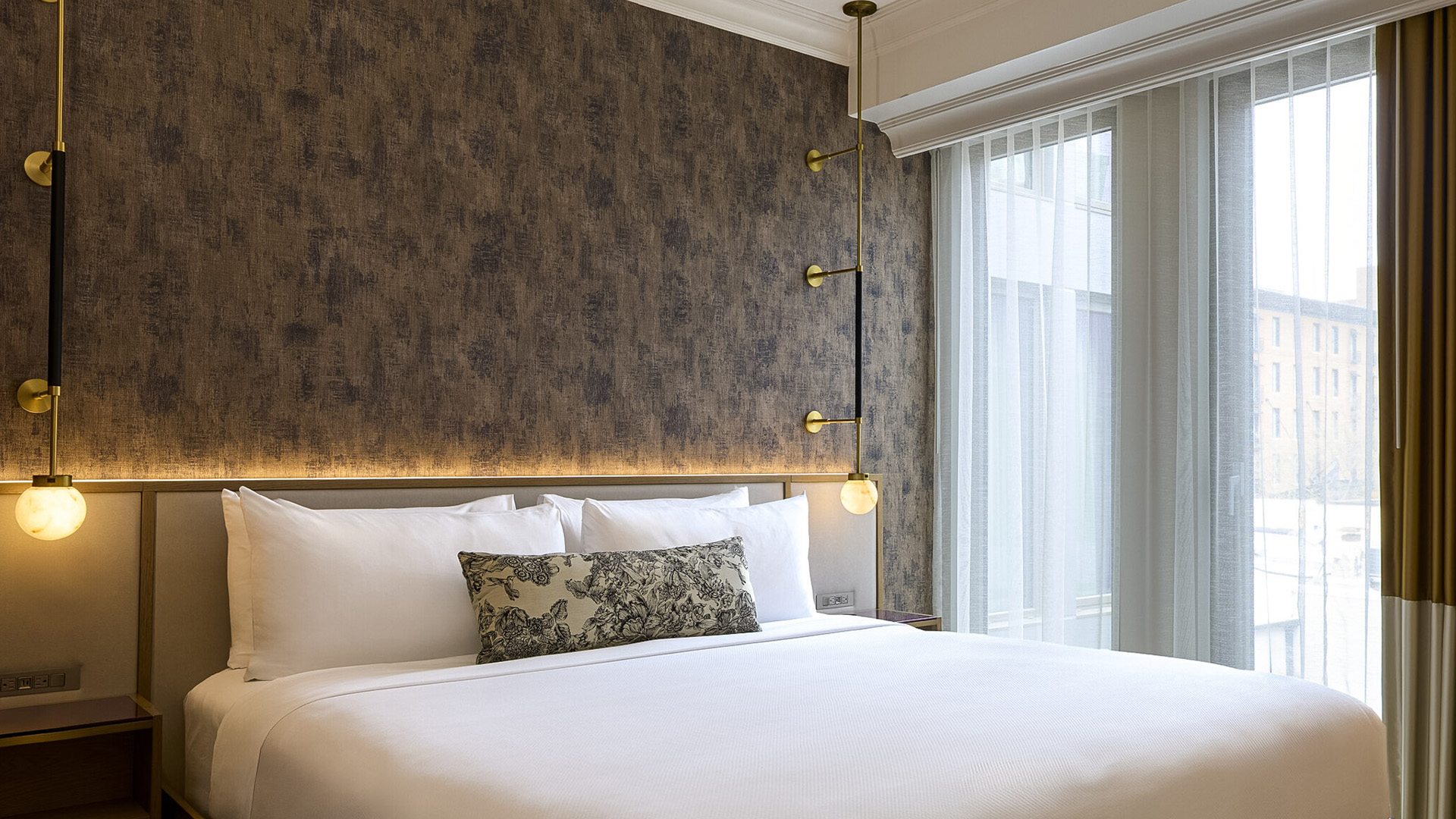 a bed with white sheets and pillows in a room