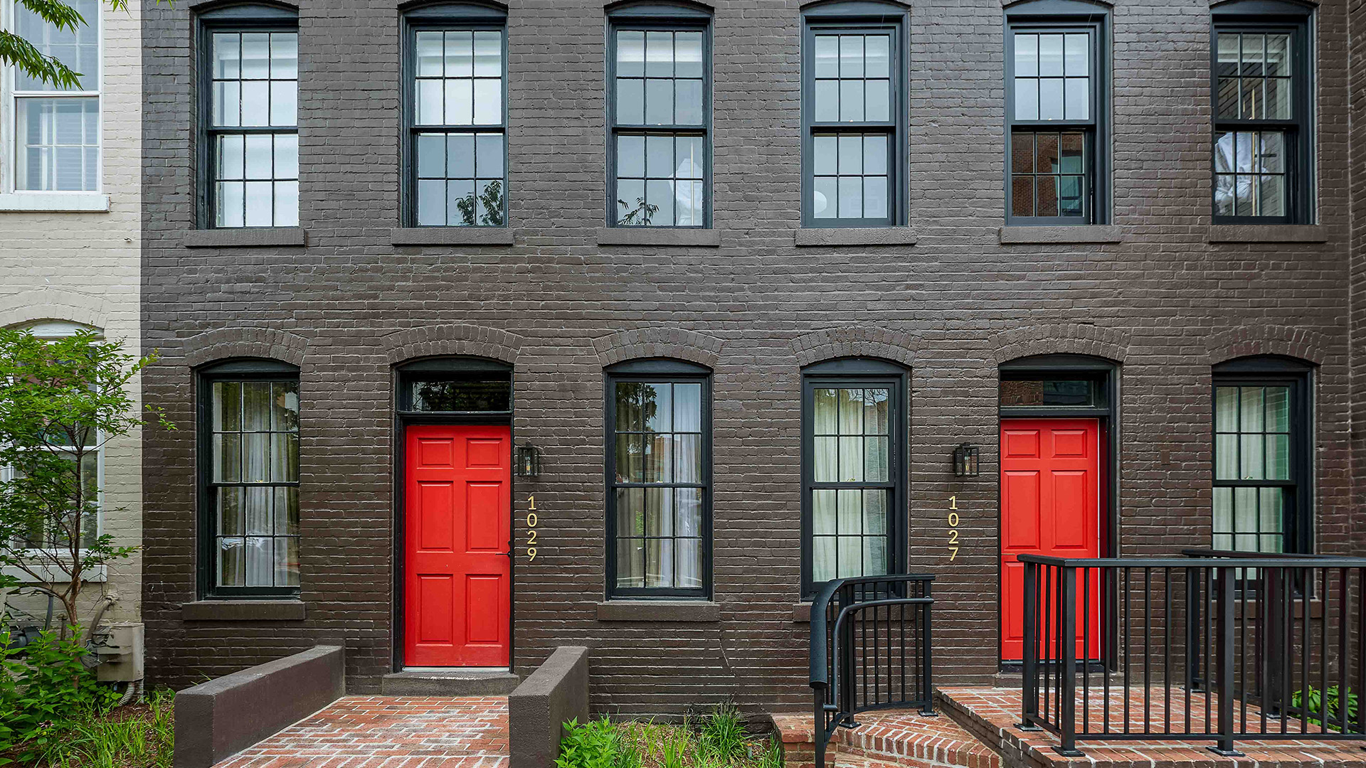 a brown building with red doors and stairs