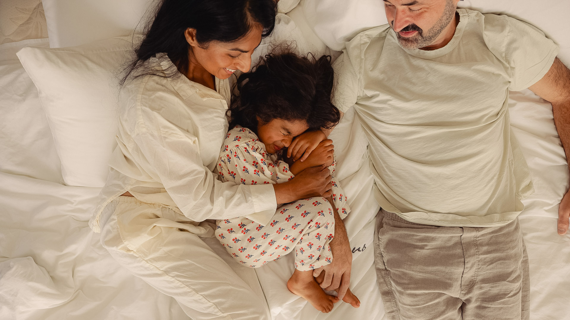 a man and woman lying on a bed with a baby