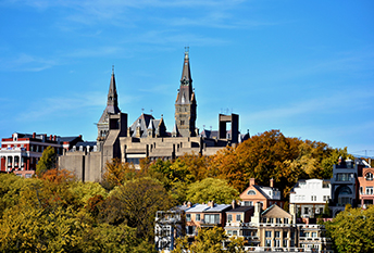 a large building with towers on top of a hill with trees in the background