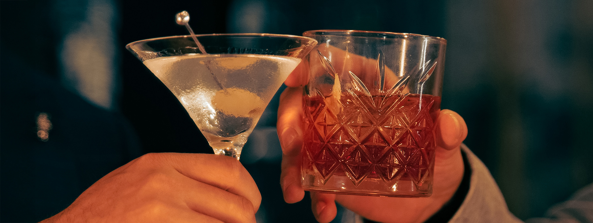 a pair of hands holding up a glass of alcohol