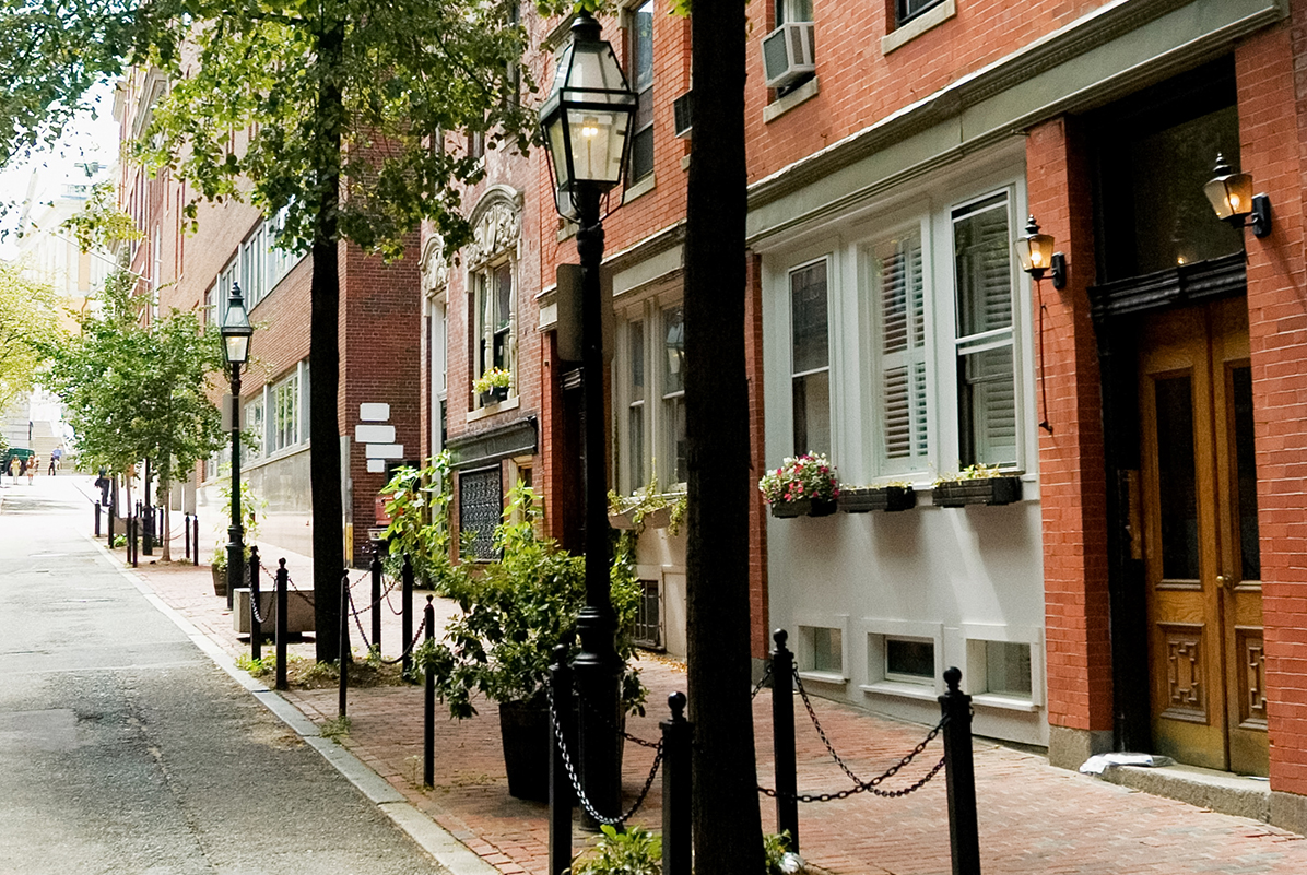 a street with a lamp post and trees with Beacon Hill in the background