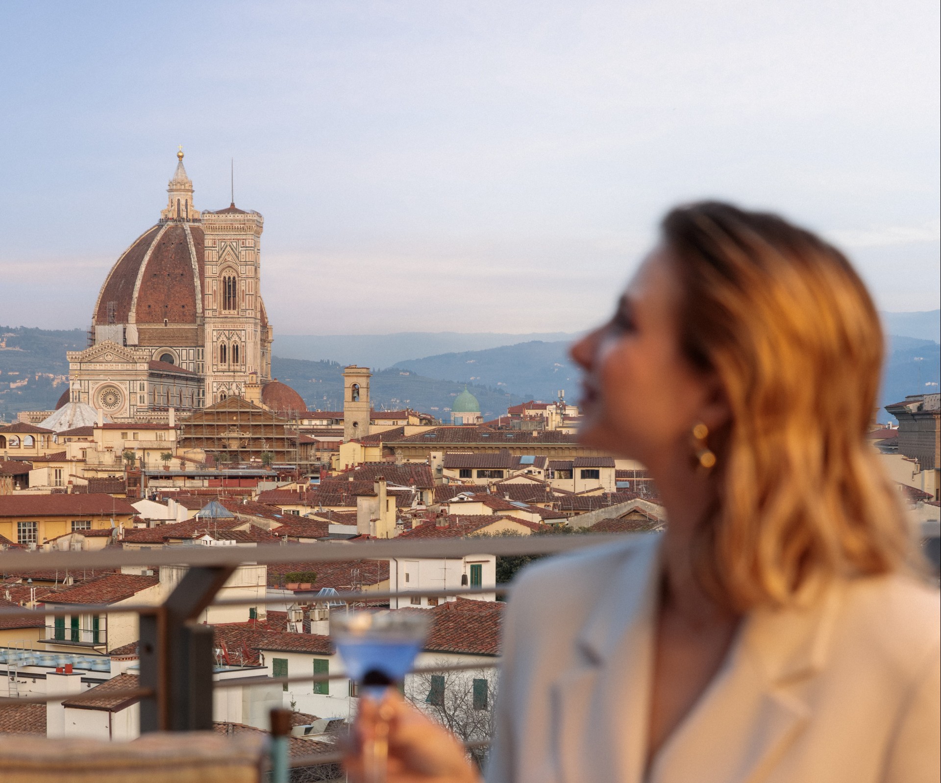 a woman holding a martini glass looking at a city