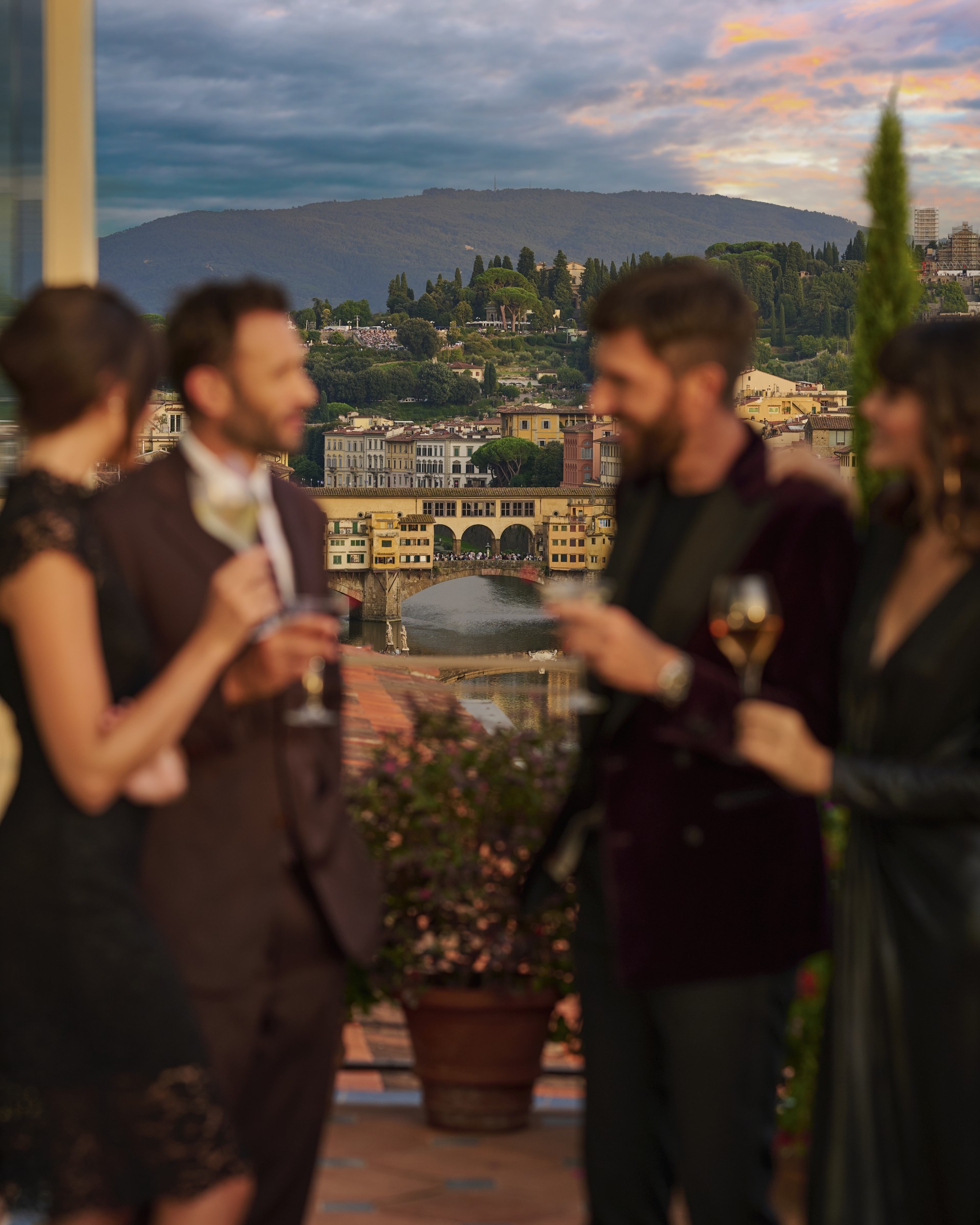 a group of people standing on a balcony with a view of a city and a river