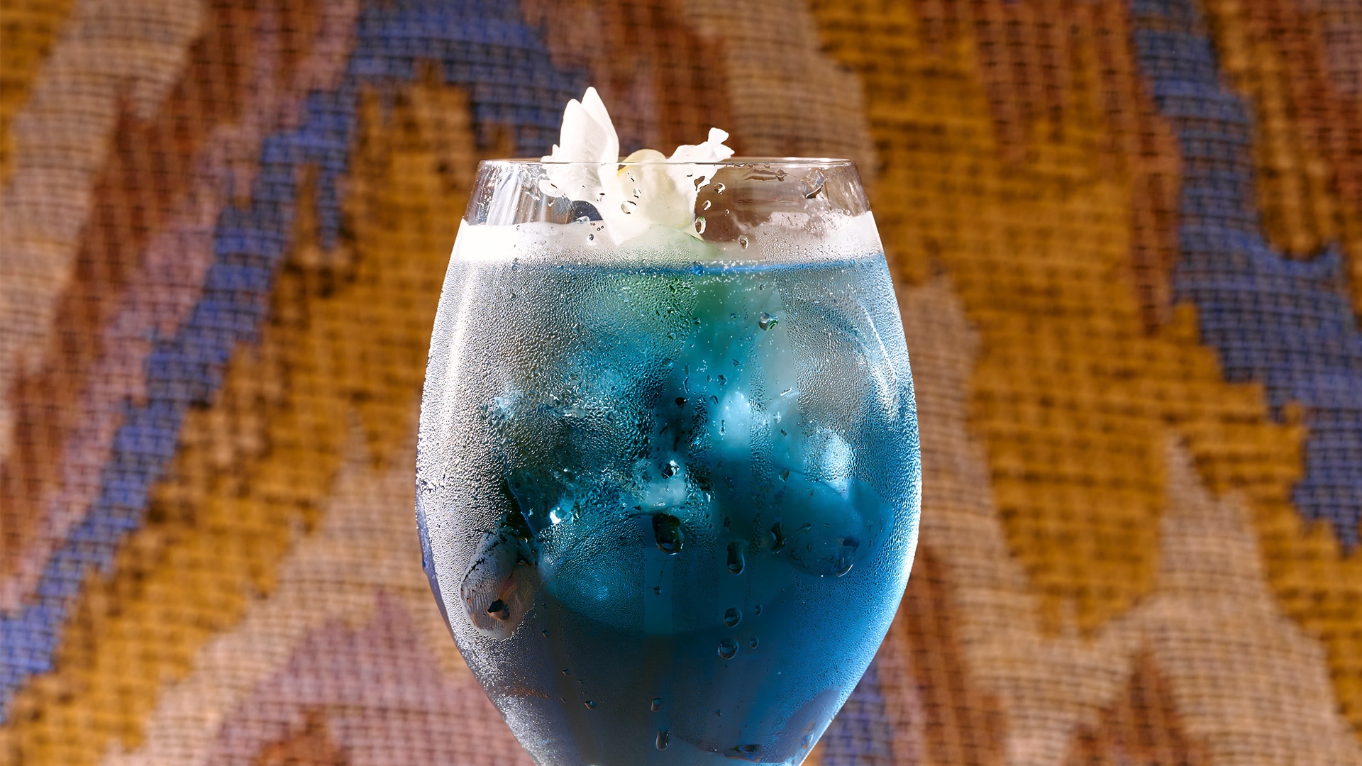 a glass with blue liquid and ice cubes in it