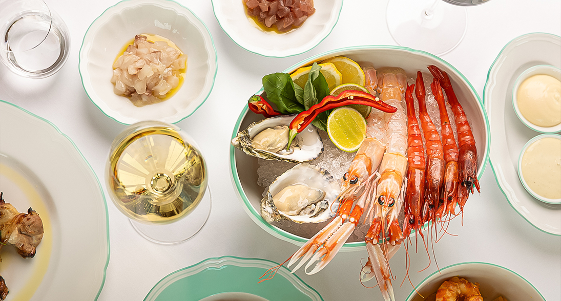 a bowl of seafood with a glass of wine