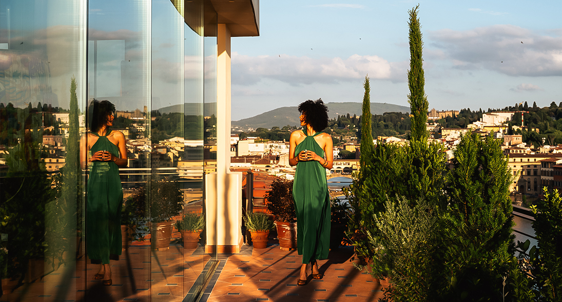 a woman in a green dress standing on a balcony overlooking a city