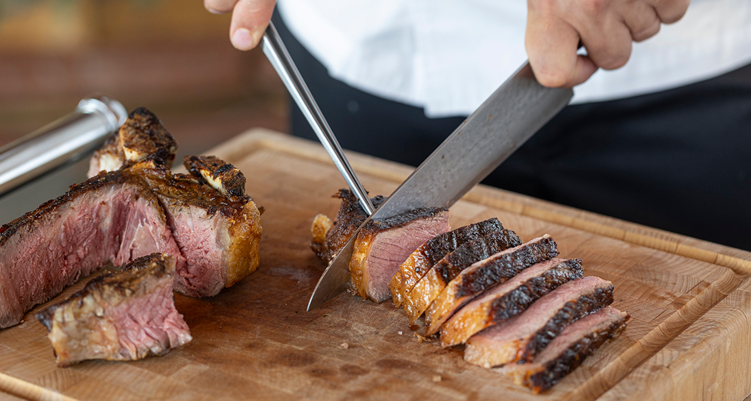 a person cutting meat on a cutting board
