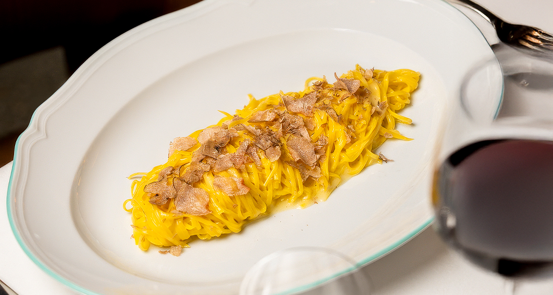 a plate of pasta with bacon on top