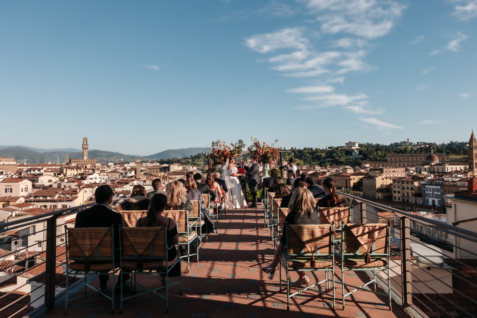 a group of people sitting on chairs on a rooftop overlooking a city