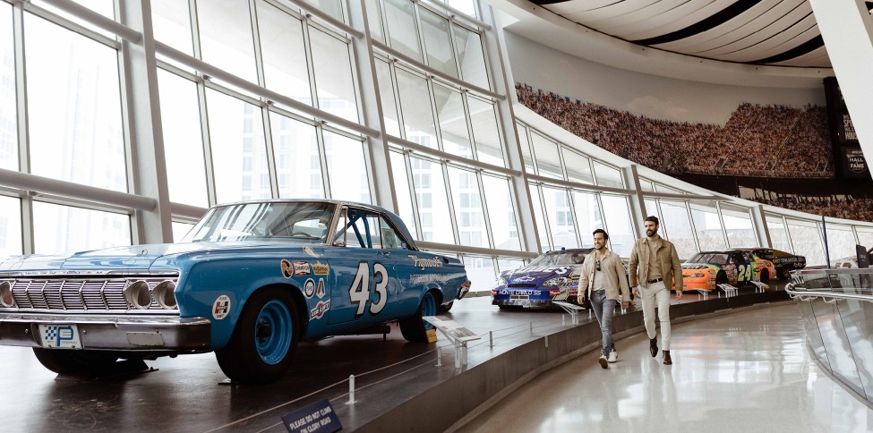 a couple of men walking in a showroom with cars