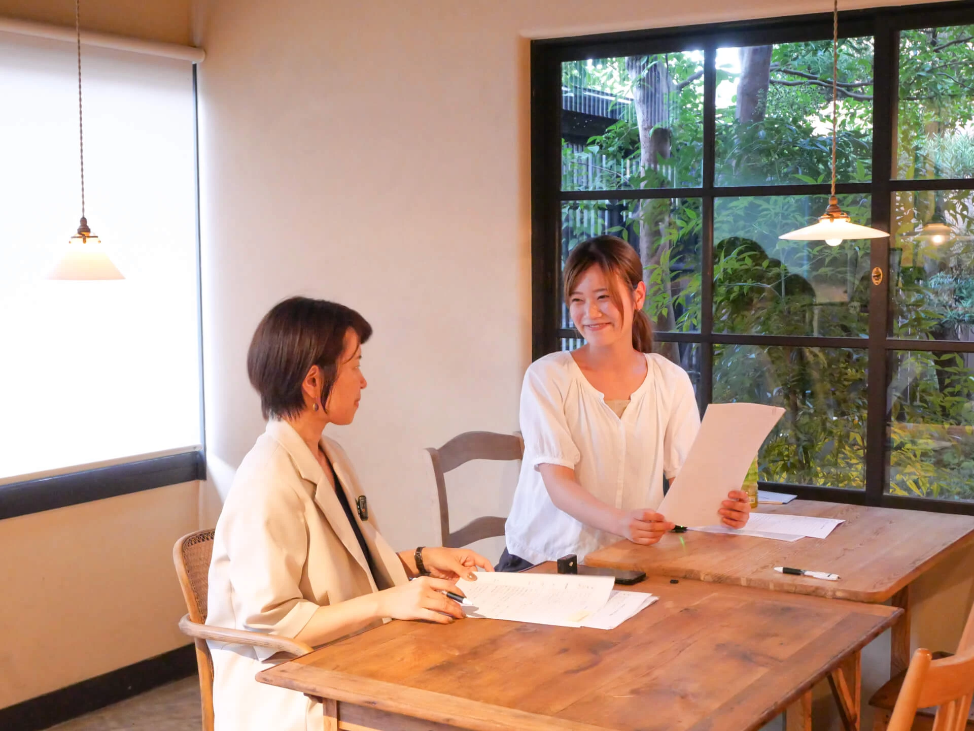 a woman sitting at a table with a paper and a woman holding a piece of paper