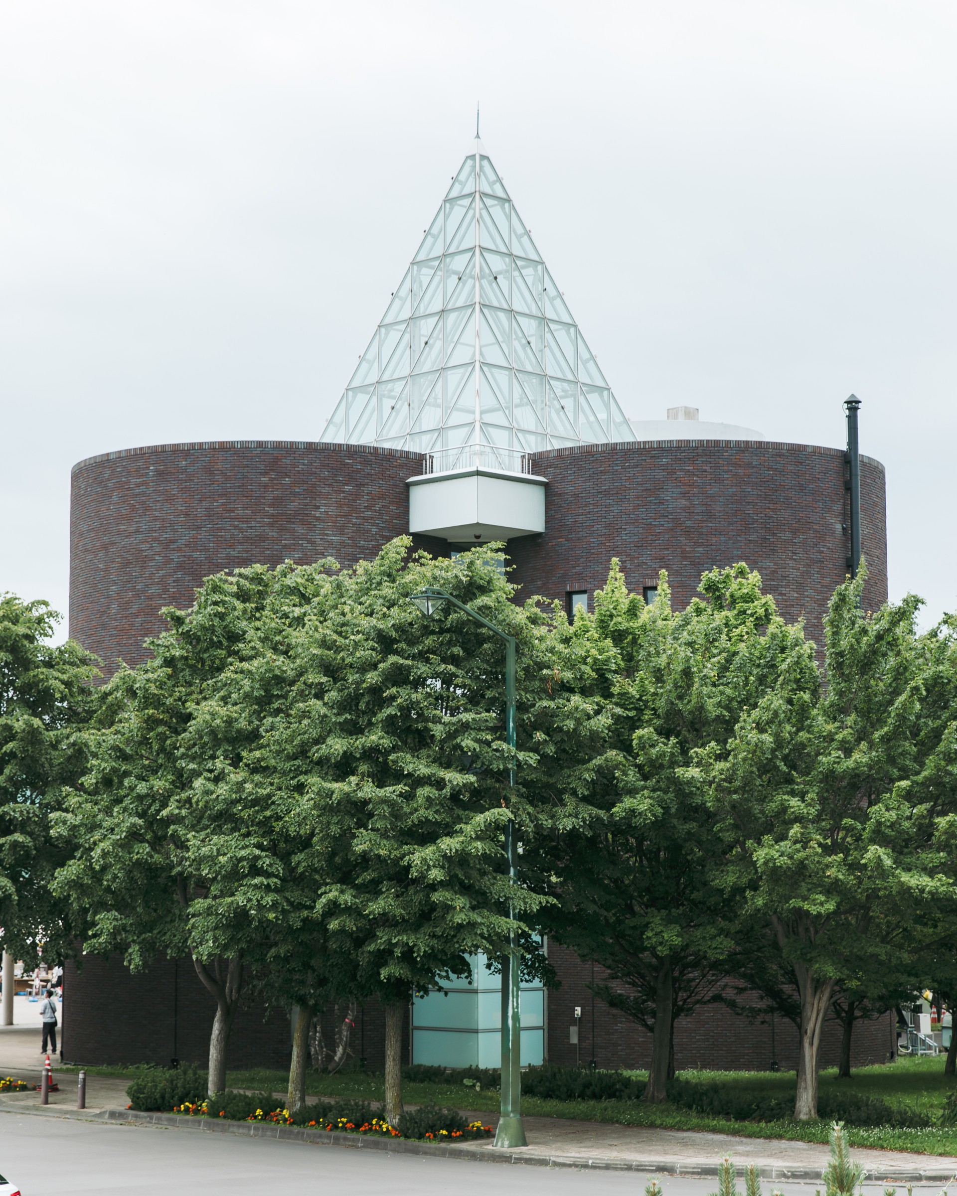 a building with a triangular glass roof and trees